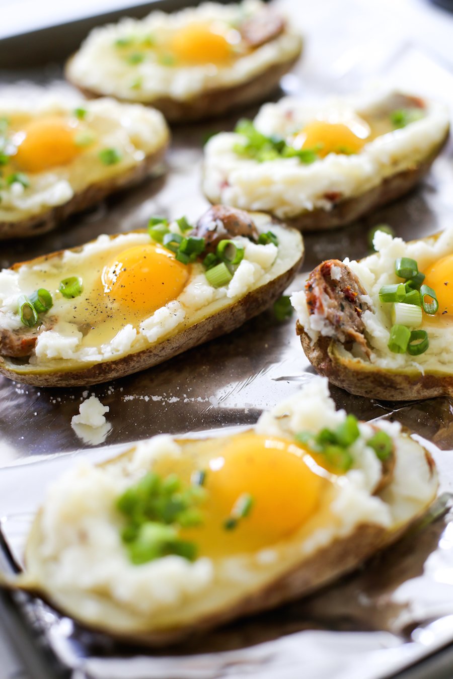 Try making these twice baked breakfast potatoes filled with chicken sausage and topped with an egg, bacon, green onions, and cheese! It is sure to be a hit at your next brunch! | saltycanary.com