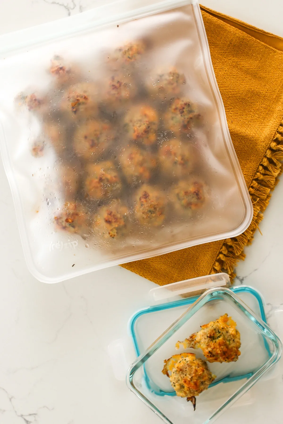 Cheesy Broccoli Turkey Meatballs in a freezer bag with 2 additional meatballs in a glass food storage container