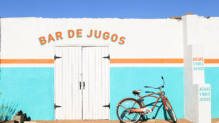 White and turquoise wall with orange stripe outside of restaurant with 
